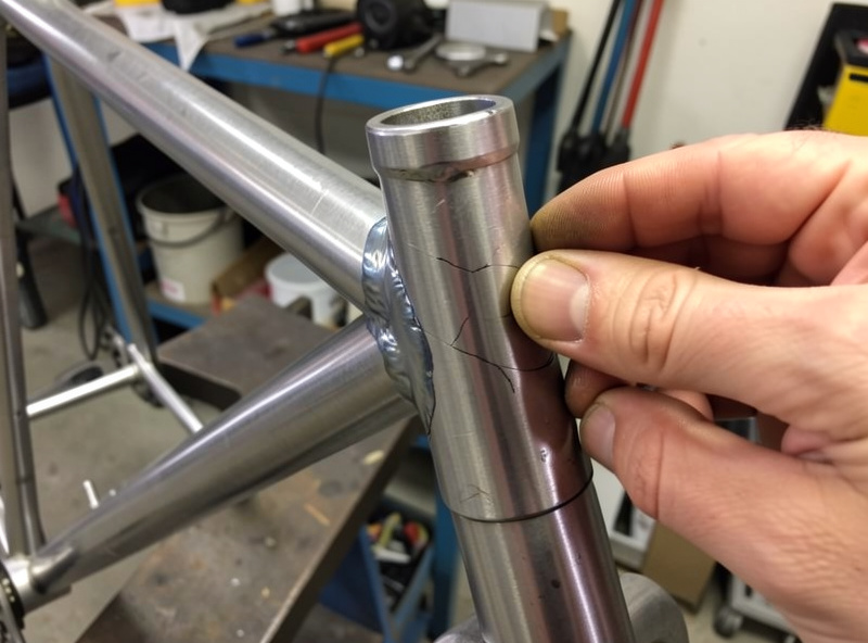A steel hardtail bicycle frame on a repair stand being inspected as a conversion donor candidate