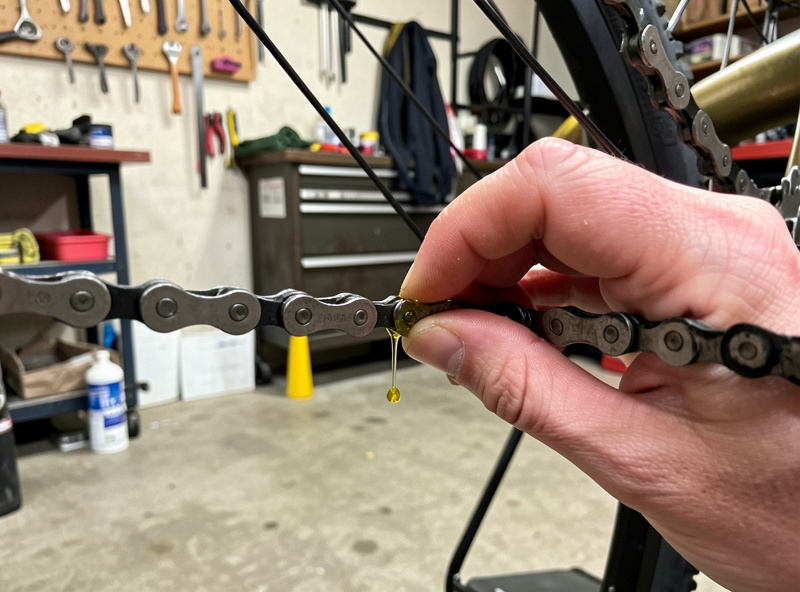 Applying winter wet lube to a clean e-bike chain in a garage